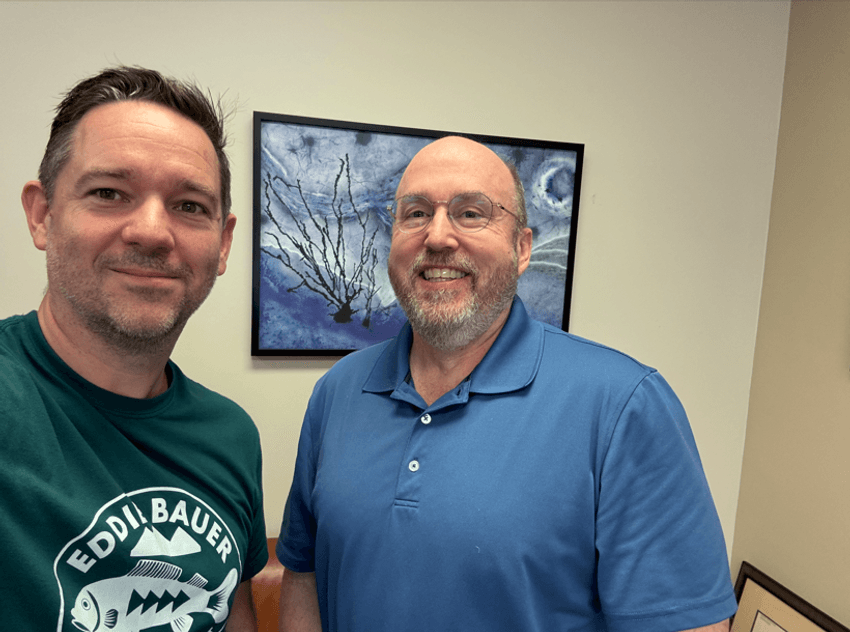 Sean Bendall wears a green T-shirt and stands beside Thomas Montine, who wears a blue shirt. They both stand in front of an image of a microglia. Sean Bendall wears a green T-shirt and stands beside Thomas Montine, who wears a blue shirt. They both stand in front of an image of a microglia.